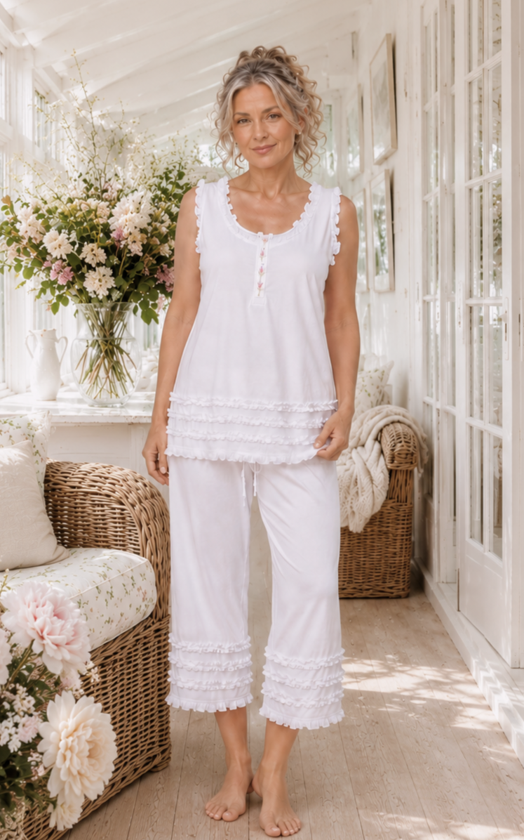Model wearing white ruffled cotton pyjamas in a sunlit sunroom
